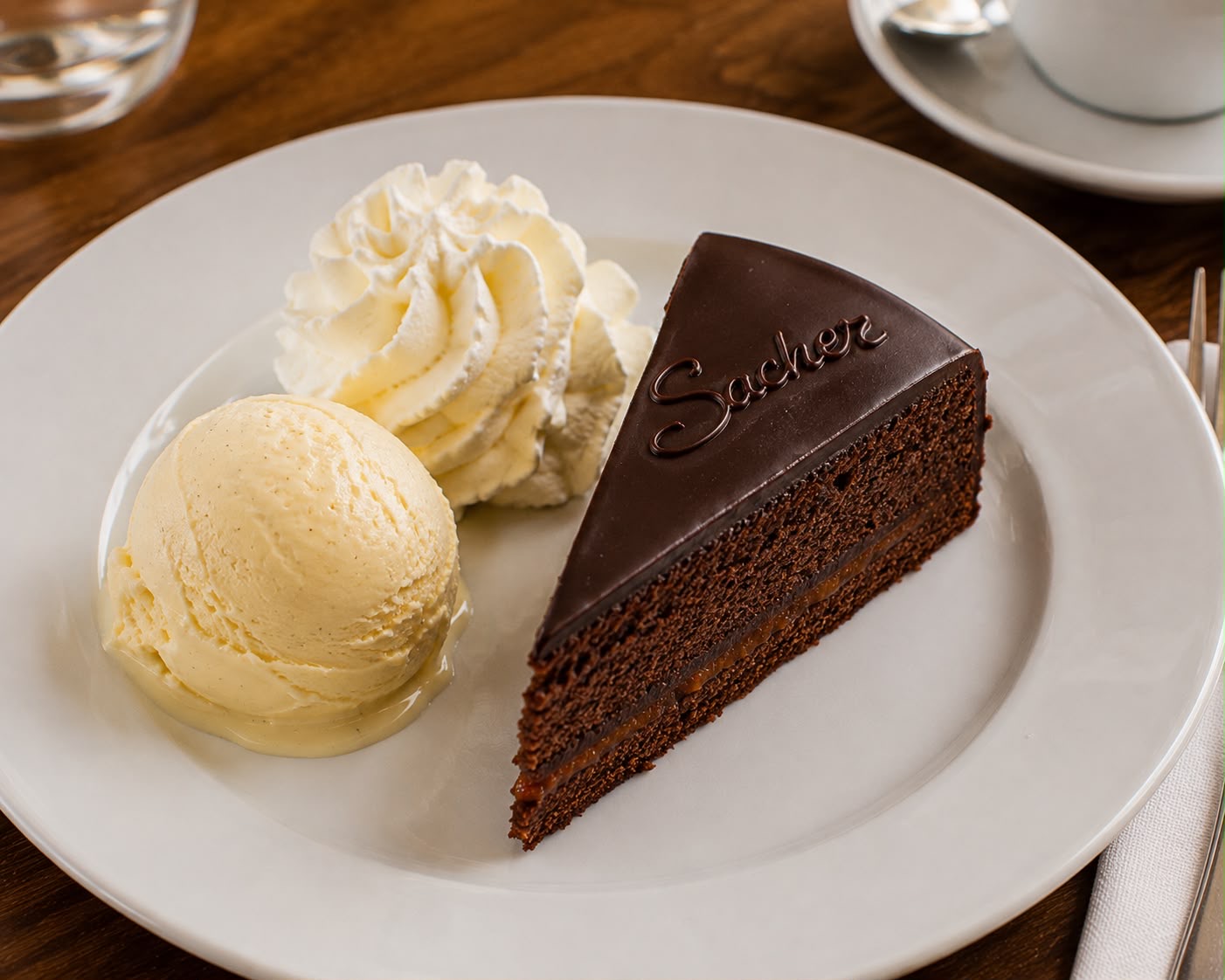 Sachertorte mit einer Kugel Vanilleeis und Schlagobers